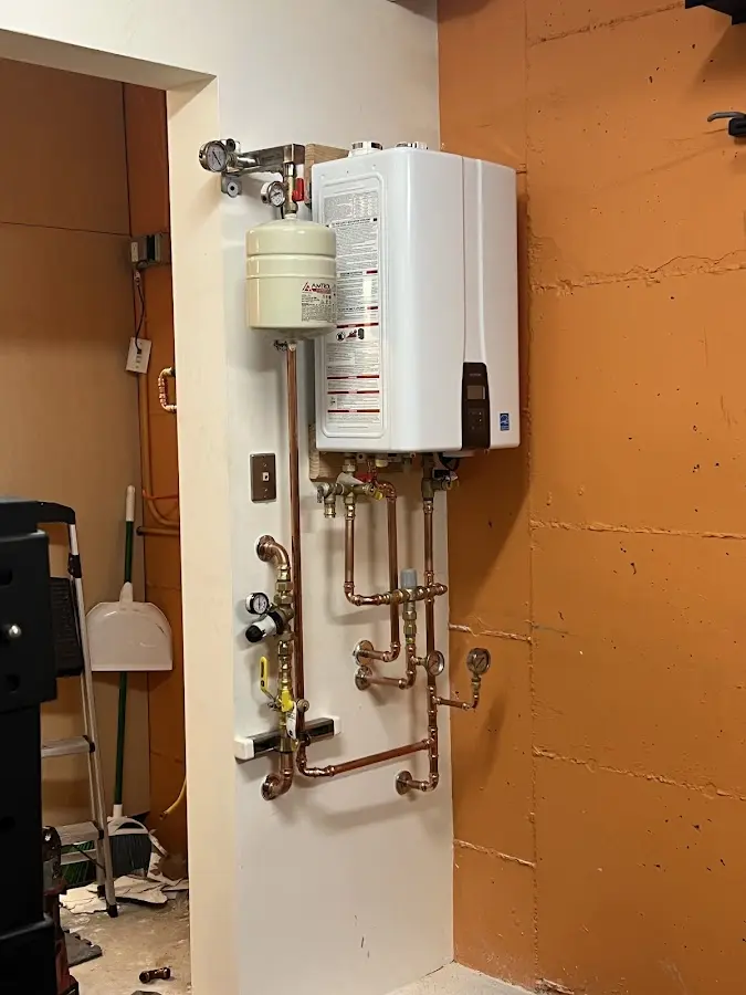 Plumbing technician inspecting water heater connections in Carlisle